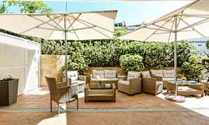 Utemöbler med parasoller på en stenterass omgiven av grönska. (AI-genererad text)