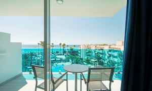 Utsikt från en balkong med två stolar och ett bord mot havet och en hotellpool. (AI-genererad text)