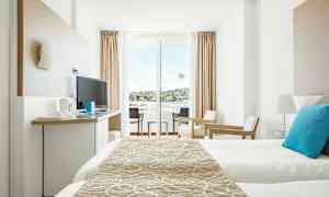 Ett modernt hotellrum med sängar, tv och sittmöbler, samt en balkong med utsikt. (AI-genererad text)