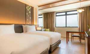 Ett hotellrum med två enkelsängar, ett stort fönster och ett skrivbord. (AI-genererad text)