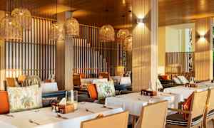 En restaurang med dukade bord och hängande lampskärmar i flätad design. (AI-genererad text)