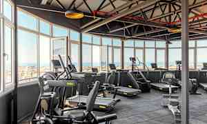 Ljusa gym med träningsmaskiner och utsikt genom stora fönster. (AI-genererad text)