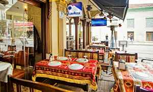 En utomhusservering vid en restaurang med bord, stolar och dukar med mönster. (AI-genererad text)