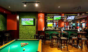 Ett biljardbord i en bar med flera TV-skärmar som visar sport. (AI-genererad text)