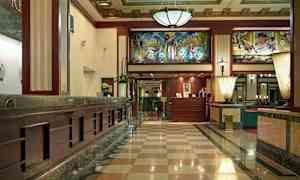 Entréhall med marmorgolv, receptionsdisk och dekorativt innertak. (AI-genererad text)