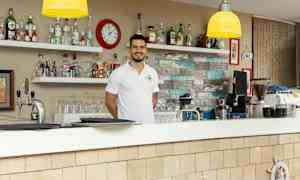 En bar med hyllor fyllda med flaskor och ett klocka på väggen. (AI-genererad text)