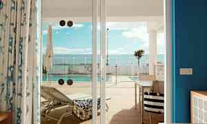 Bild av en solstol och en pool, sedd från en terrass genom glasdörrar. (AI-genererad text)