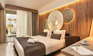 Hotellrum med en stor säng, dekorerad vägg och öppen balkong med utsikt. (AI-genererad text)