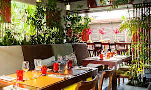 Ett inbjudande restaurangområde med växter, träbord och dekorativa glas. (AI-genererad text)