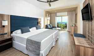 Hotellrum med två enkelsängar, sittgrupp och balkong. (AI-genererad text)