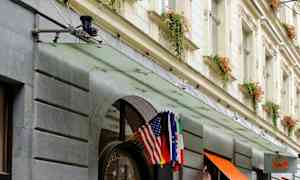 Hotellfasad med ingång dekorerad med blomkrukor och flaggor. (AI-genererad text)