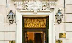 Entré till byggnad med skylt Antica Roma, omgiven av två flaggor och växtdekorationer. (AI-genererad text)