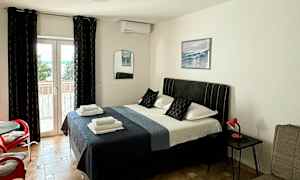 Ett sovrum med en dubbelsäng, sittmöbler och en glasdörr ut mot en balkong. (AI-genererad text)