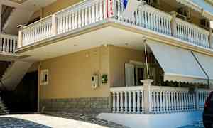 Byggnad med balkonger och markiser vid en stenlagd entré. (AI-genererad text)