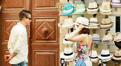 En person provar en hatt vid ett försäljningsbord med olika hattar. (AI-genererad text)