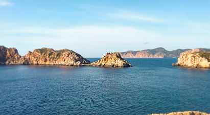 Kustlandskap med klippiga öar i havet under en klar blå himmel. (AI-genererad text)