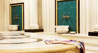 Bild av ett traditionellt hamam med marmorytor och vattenkranar. (AI-genererad text)