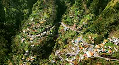 Utsikt över en dal med terrasserade odlingsområden och hus. (AI-genererad text)