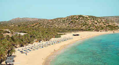 Sandstrand med turkost hav, solstolar och parasoller. Bakgrund med vegeterade berg. (AI-genererad text)