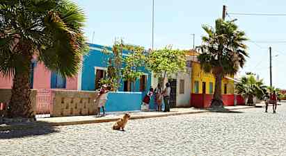 En gata med färgglada hus, palmer och människor som promenerar. (AI-genererad text)