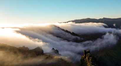 Moln sveper över en bergskedja vid soluppgång eller solnedgång. (AI-genererad text)