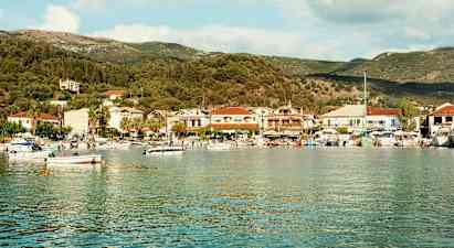 En havsvik med småbåtar och en kuststad fylld med hus och träd i bakgrunden. (AI-genererad text)