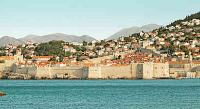 Stenstadsmurar och röda tak vid havskust. (AI-genererad text)