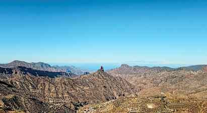 Landskap med berg och en distinkt klippformation under blå himmel. (AI-genererad text)