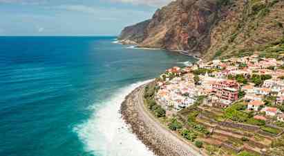 Vy över en kustlinje med en by på klippan och havet i bakgrunden. (AI-genererad text)