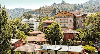 En samling bostadshus bland träd vid en sluttning. (AI-genererad text)