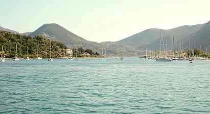 En vy över en vik med segelbåtar och omgivande gröna kullar. (AI-genererad text)