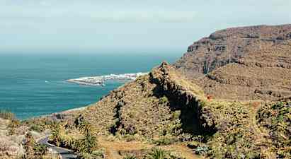 Vy över bergigt landskap och kust med hav och en hamnanläggning. (AI-genererad text)