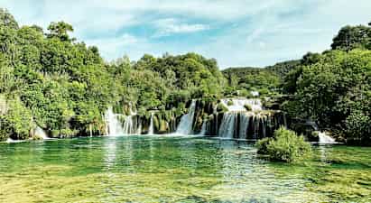 Ett naturskönt vattenfall omringat av frodig grönska. (AI-genererad text)