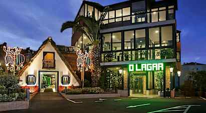 En byggnad med en traditionell stråtaksvit och en modern glaspanel struktur bredvid, upplyst på kvällen med lysande dekorationer och markbelysning. (AI-genererad text)