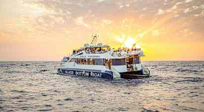 En glasbottenbåt med människor ombord åker på havet under en solnedgång. (AI-genererad text)