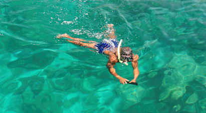 En person simmar i klart vatten med snorkelutrustning. (AI-genererad text)