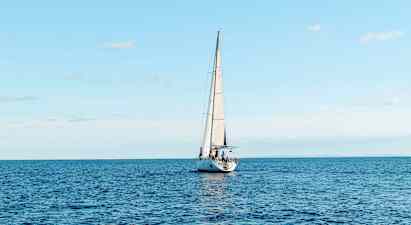 En segelbåt seglar på ett öppet hav under en klar himmel. (AI-genererad text)