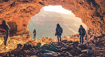 En grupp människor utforskar en grotta med utsikt över ett bergigt landskap. (AI-genererad text)