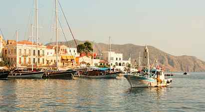 En hamn med båtar och byggnader, berg syns i bakgrunden. (AI-genererad text)