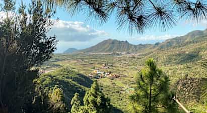 Vy över ett grönt dalområde med byar och berg i bakgrunden. (AI-genererad text)