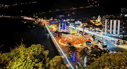 Stad vid havet nattetid med belysning och dekorationer. (AI-genererad text)