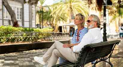 Personer sitter på en parkbänk i en stadsmiljö. (AI-genererad text)