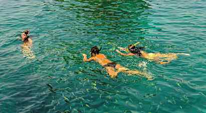 Personer som snorklar i klart vatten med fiskar omkring. (AI-genererad text)