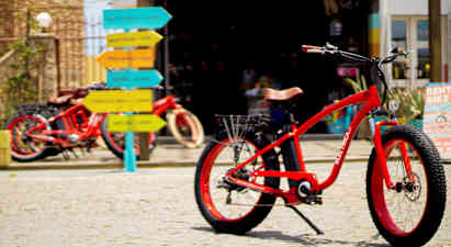 Röd cykel på kullerstensyta med färgglada vägskyltar i bakgrunden. (AI-genererad text)