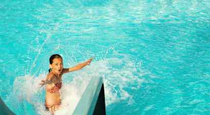 Person som åker nerför en vattenrutschkana in i en pool. (AI-genererad text)