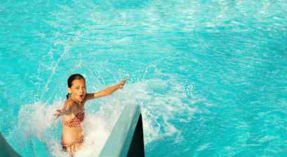 Person som åker nerför en vattenrutschkana in i en pool. (AI-genererad text)