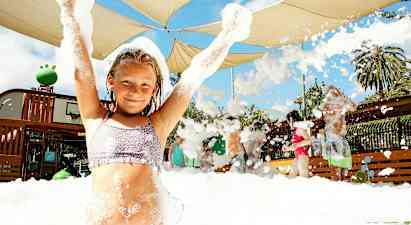 En grupp människor njuter av en skummig aktivitet under ett skärmtak utomhus. (AI-genererad text)