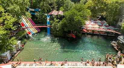 Vattenpark med flera vattenrutschbanor och badområde omgiven av grönska. (AI-genererad text)