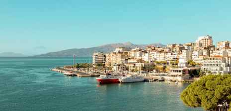 Vy över en stad vid havet med småbåtshamn och byggnader längs kusten. (AI-genererad text)