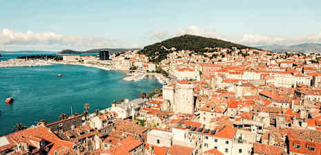 Vy över en stad med röda tak, kustlinje och marina. (AI-genererad text)